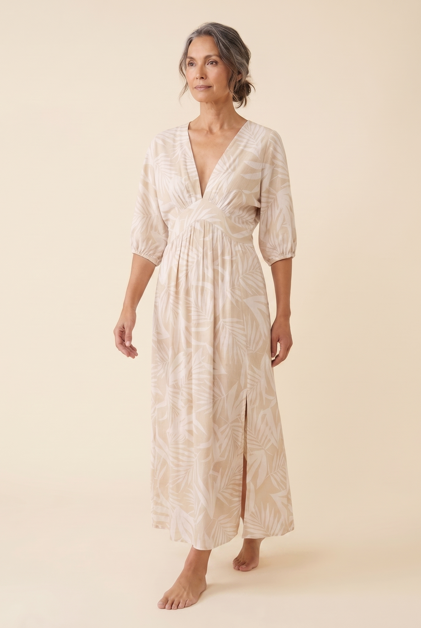 Beige tropical print maxi dress, walking pose on model, warm cream studio background