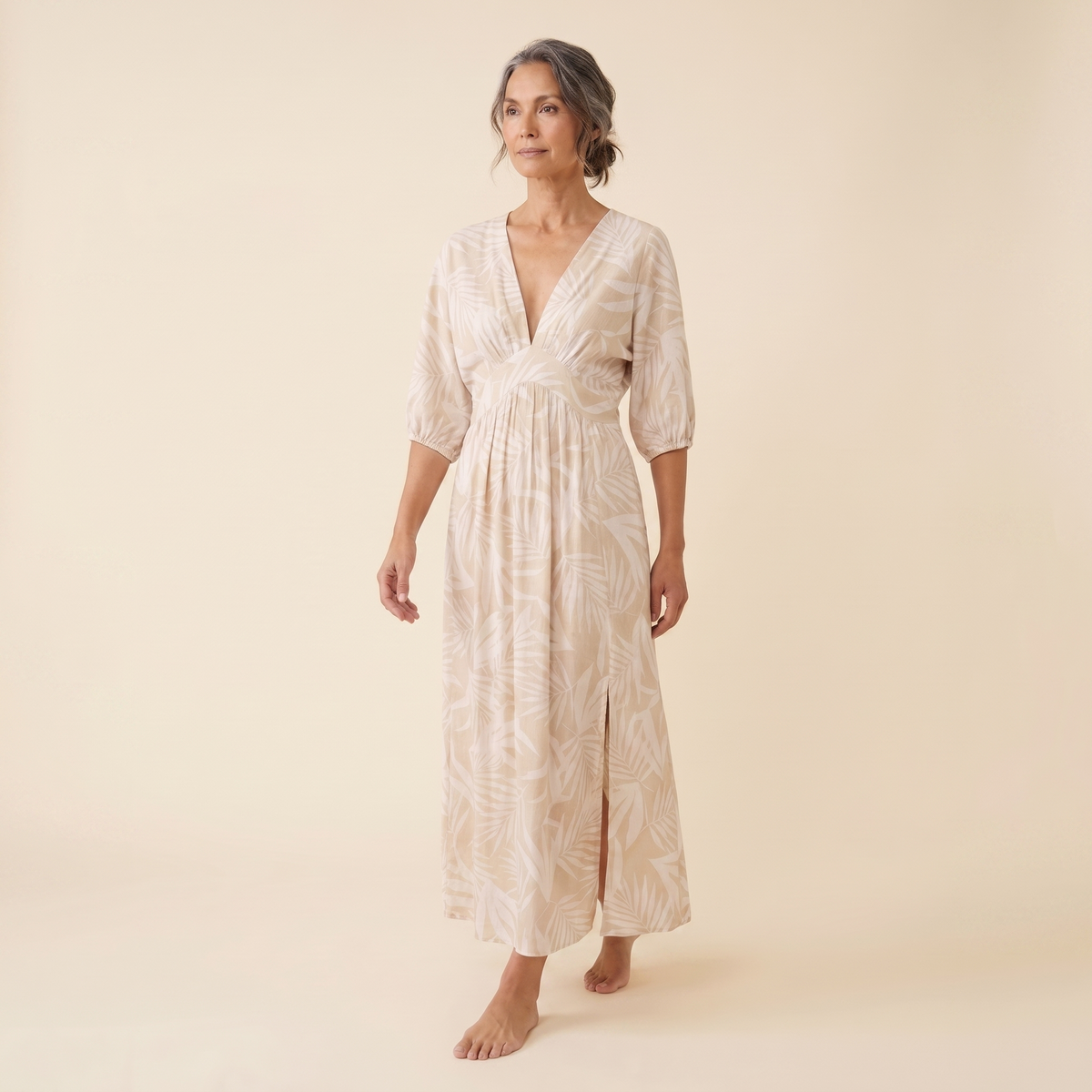 Beige tropical print maxi dress, walking pose on model, warm cream studio background