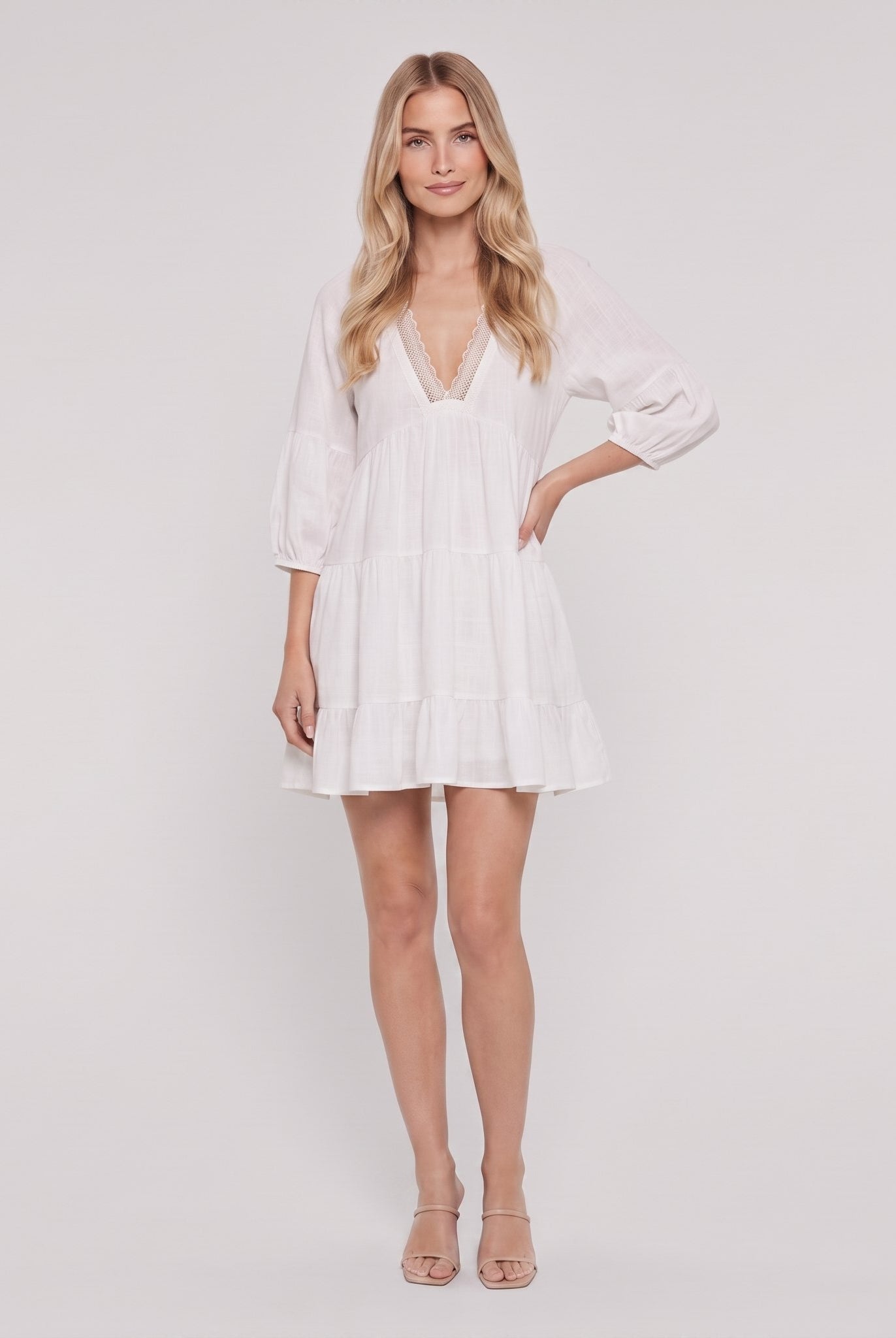 White cotton-linen tiered mini dress with crochet-lace V-neck and 3/4 puff sleeves, full-length front view