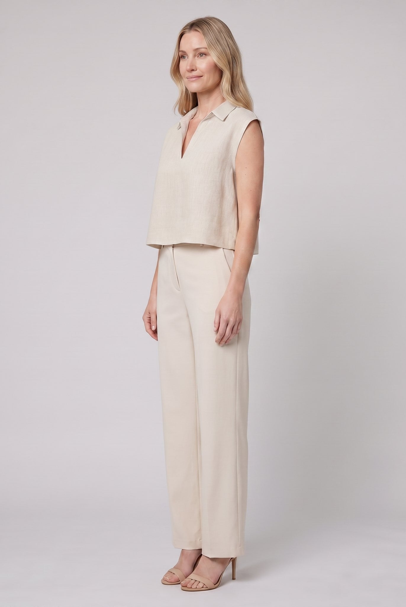 Beige linen sleeveless crop top with open collar, side view on model