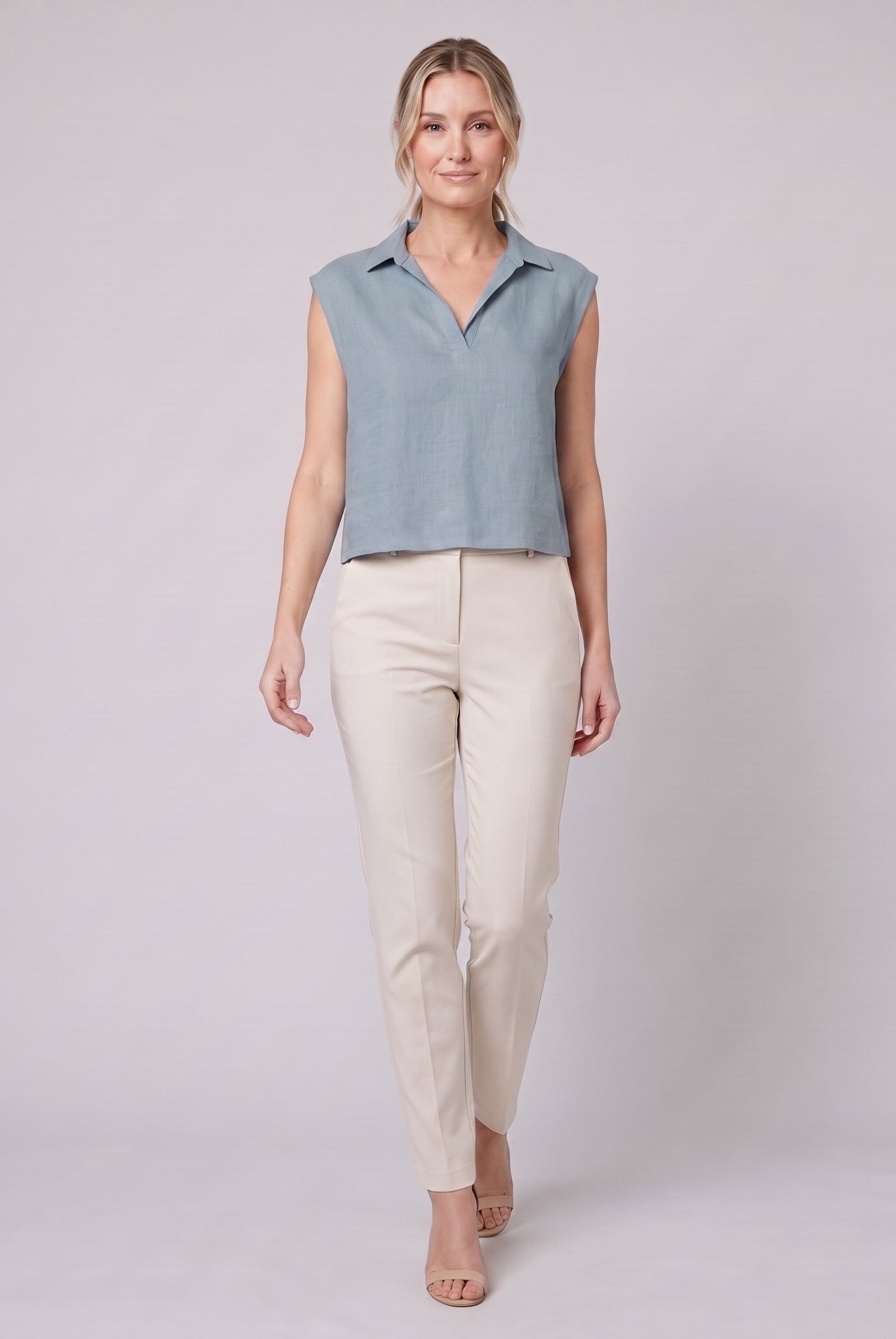 Sky blue linen sleeveless crop top with open collar, on model