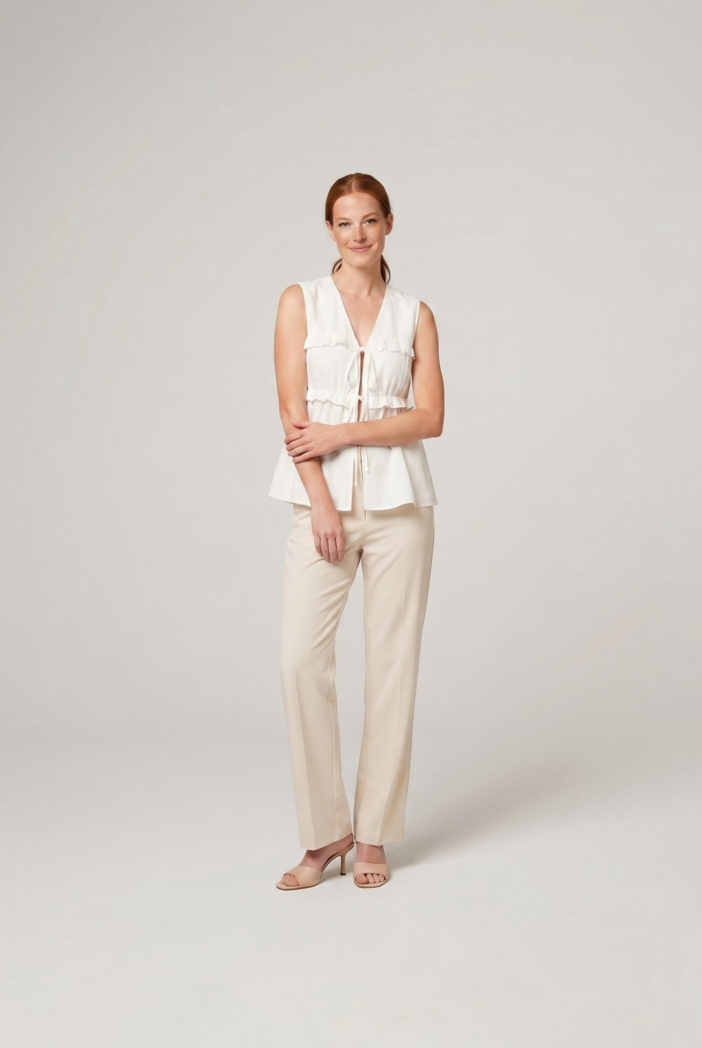 Pamela Boutique white peplum sleeveless V-neck top, model side pose