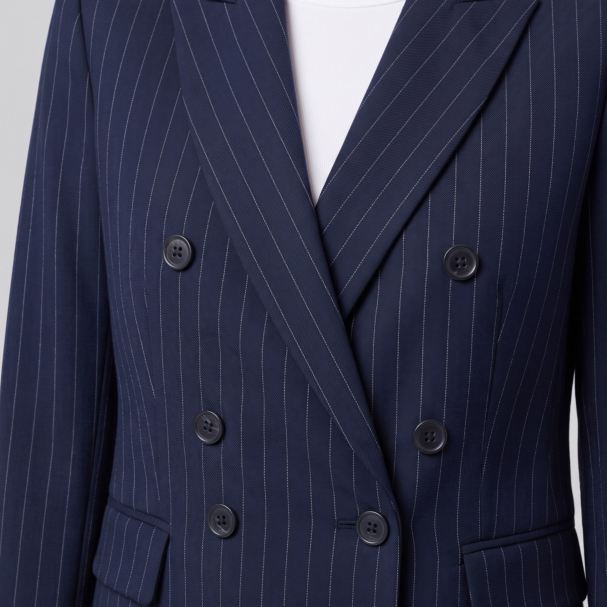 Close-up of the double-breasted buttons and pinstripe weave on the Iris suit
