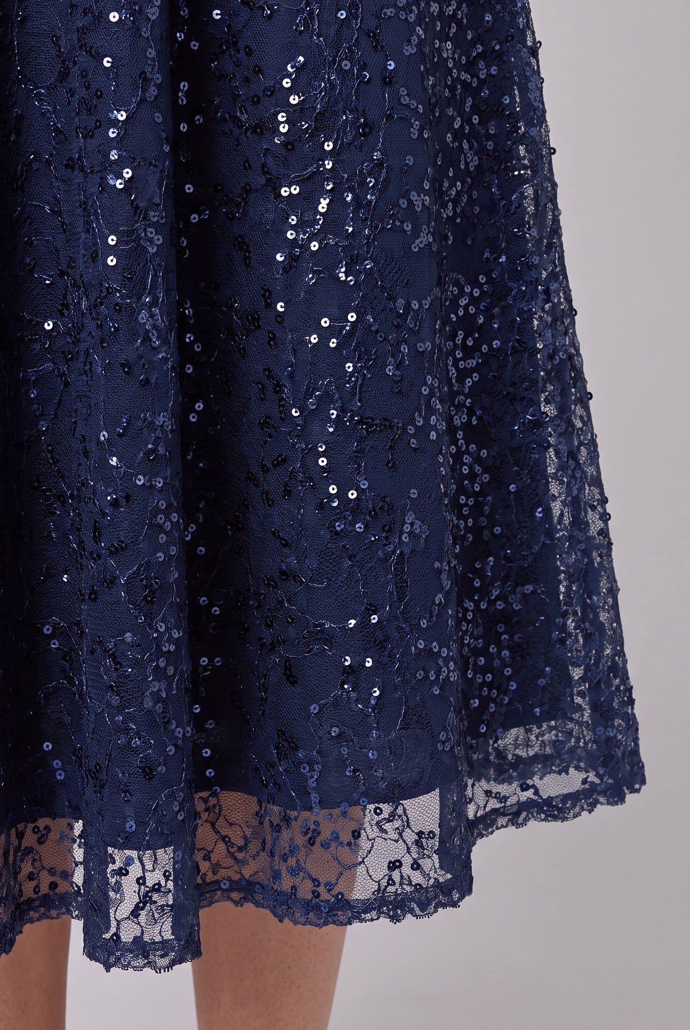 Close-up of the sequin embellishment and scalloped hem on the Novara dress