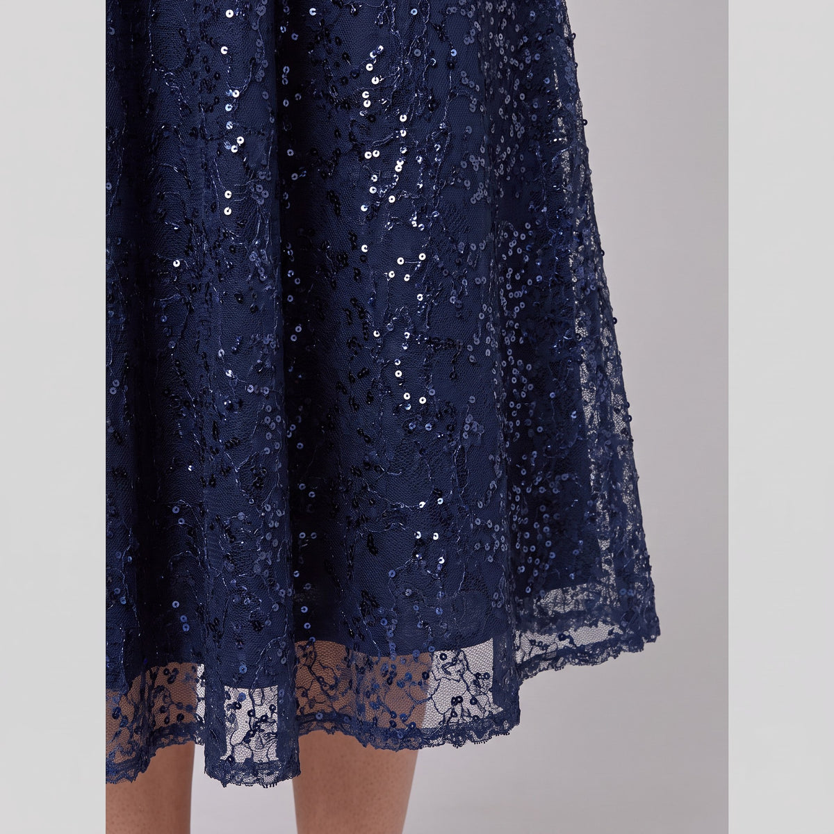 Close-up of the sequin embellishment and scalloped hem on the Novara dress