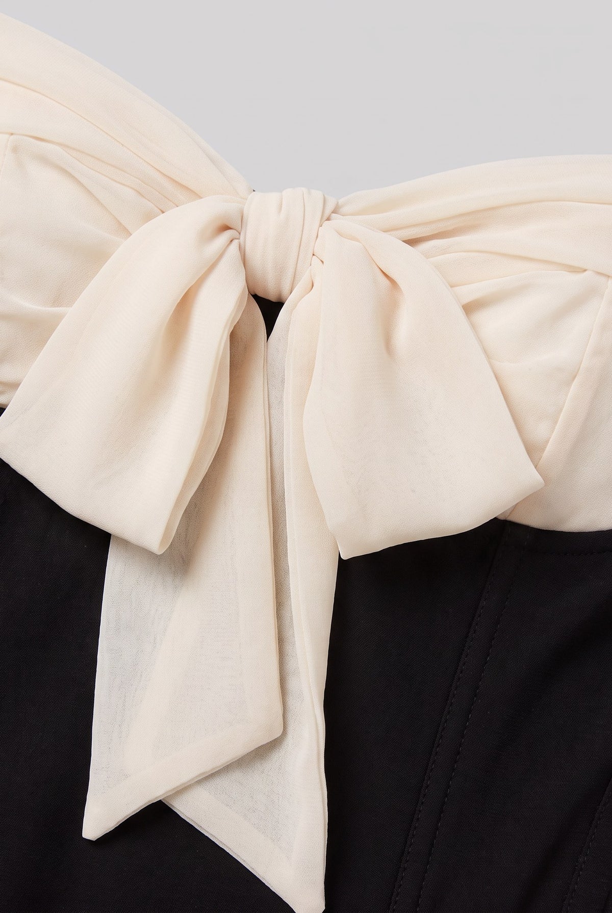 Close-up of the cream bow and corset seams on the Odette mini dress