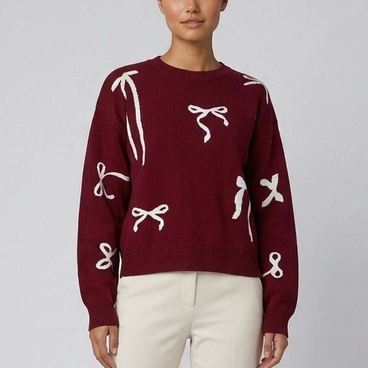 Burgundy jumper with cream bow motifs close-up