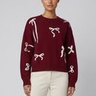 Burgundy jumper with cream bow motifs close-up