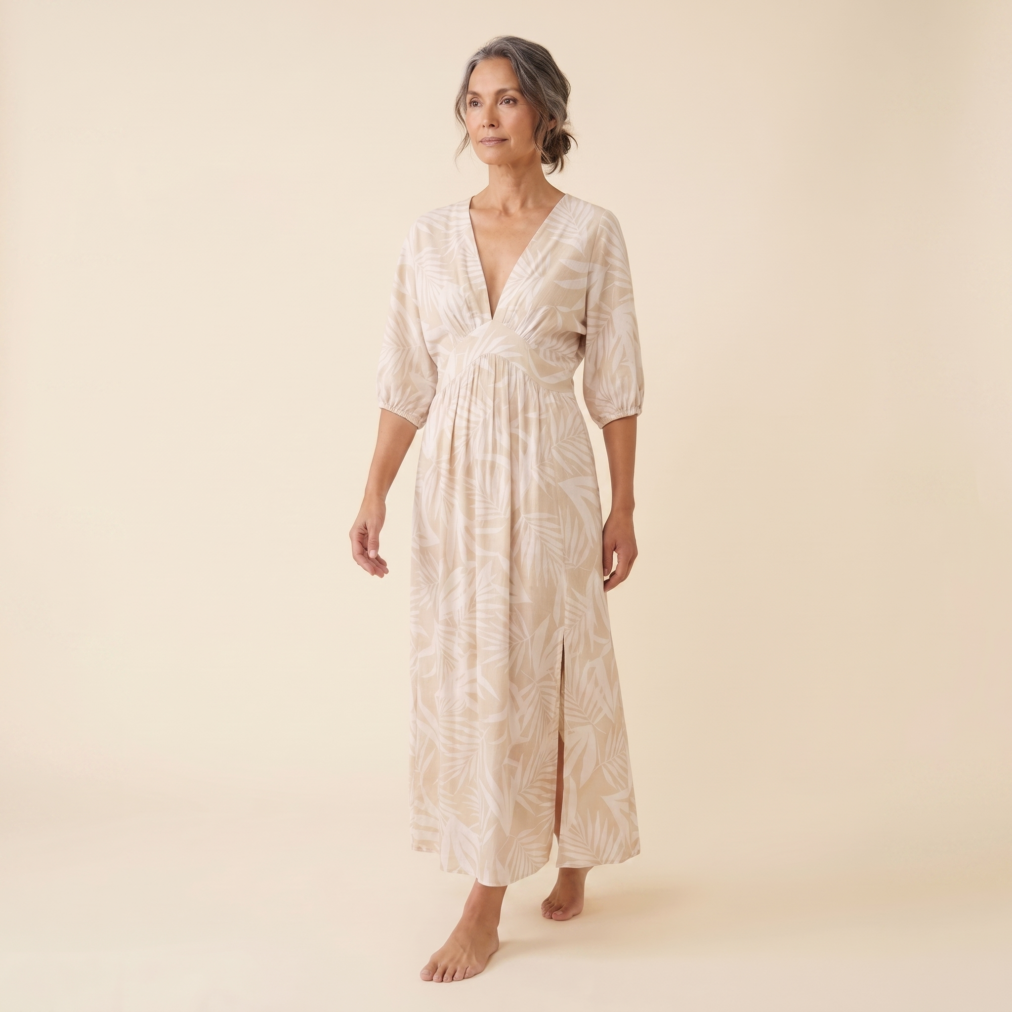 Beige tropical print maxi dress, walking pose on model, warm cream studio background
