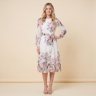 Model wearing white floral A-line midi dress with tie belt, front pose hand on hip