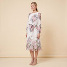 Model wearing white floral A-line midi dress with tie belt, three-quarter side angle