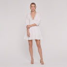 White cotton-linen tiered mini dress with lace V-neck, full-length view