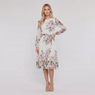 Model wearing white floral A-line midi dress with tie belt, hand on hip
