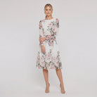 Model wearing white floral A-line midi dress with tie belt, relaxed pose