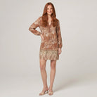 Model wearing brown floral V-neck long-sleeve shift mini dress, hand on hip