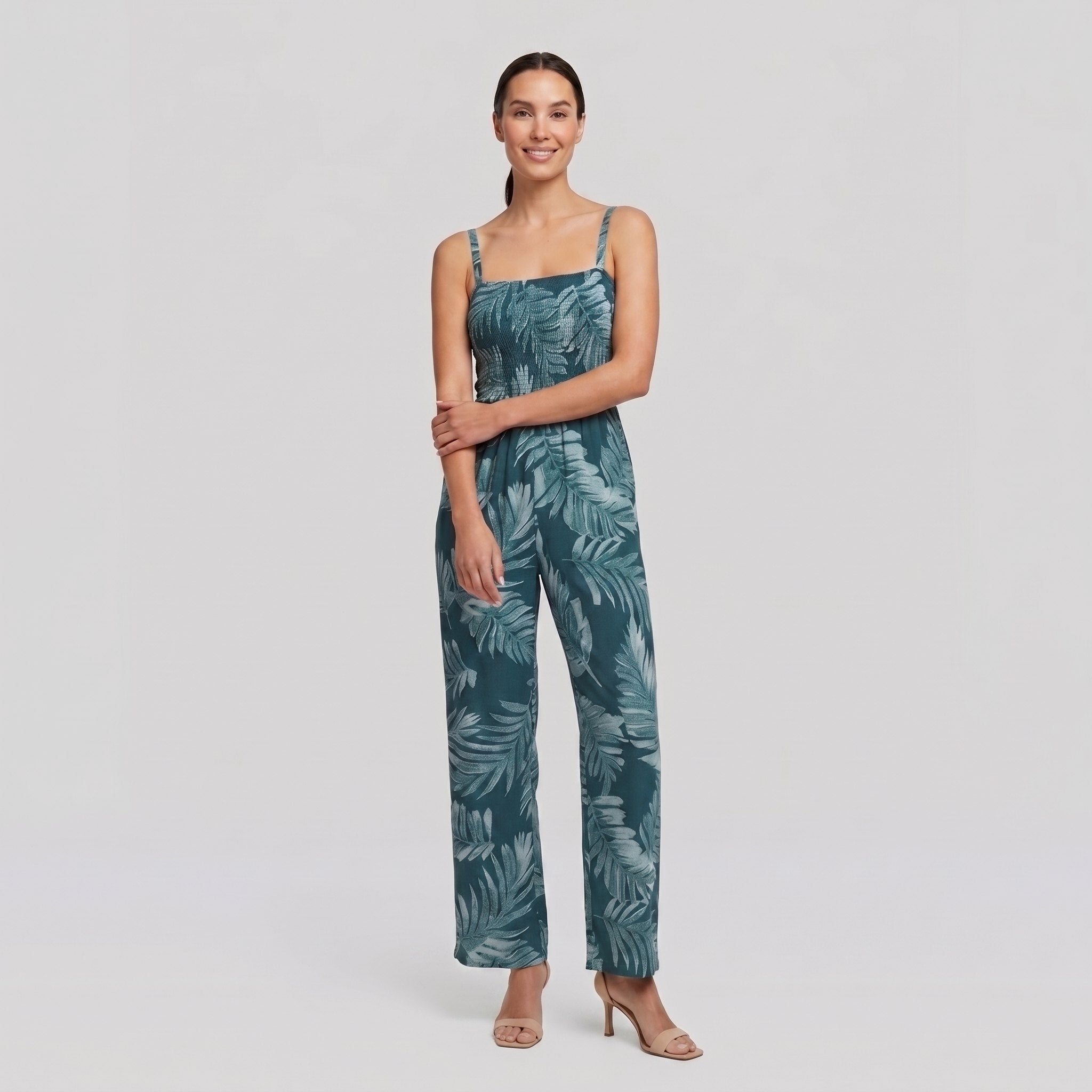 Model wearing teal wide-leg jumpsuit with smocked bodice, relaxed pose