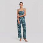 Model wearing teal wide-leg jumpsuit with smocked bodice, relaxed pose