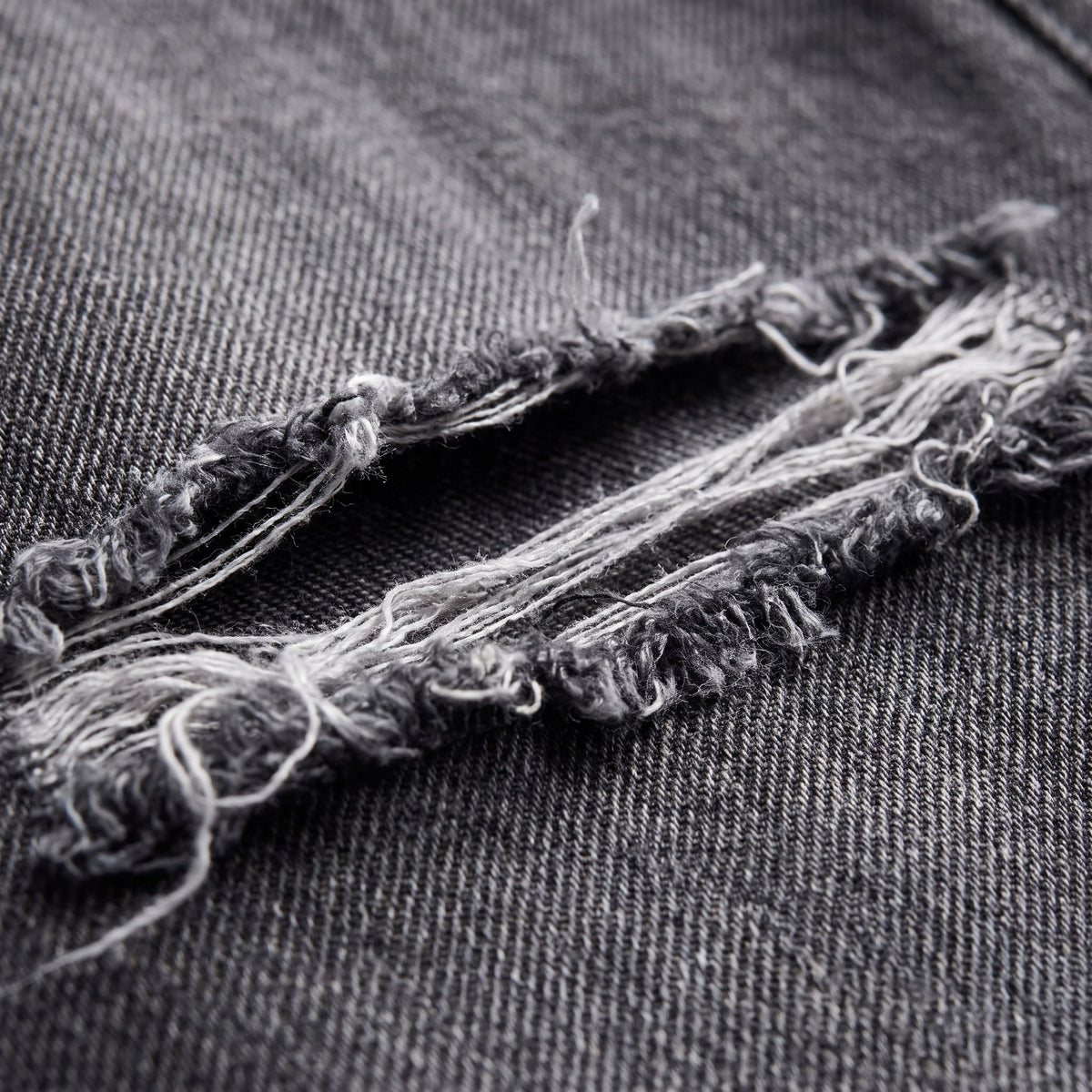 Enid baggy jeans fabric detail, distressed denim and frayed threads close-up