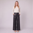Helka faux leather wide leg trousers in black, full-length view with hands in the pockets