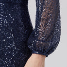 Close-up of the sequin surface and lantern sleeve cuff on the Rayven gown