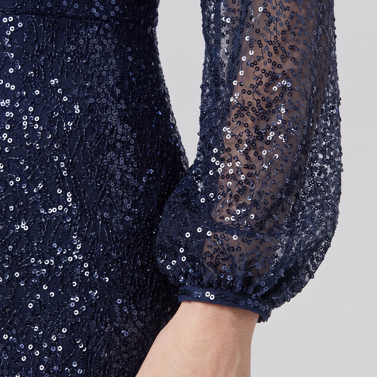 Close-up of the sequin surface and lantern sleeve cuff on the Rayven gown