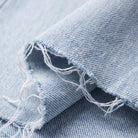Savona distressed jeans fabric detail, light wash denim and raw frayed hem close-up