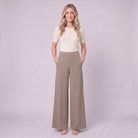 Valdis pleated wide leg trousers in taupe khaki, full-length view with hands in pockets